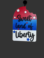 Decorative sign with 'Sweet Land of Liberty' text on a wooden background